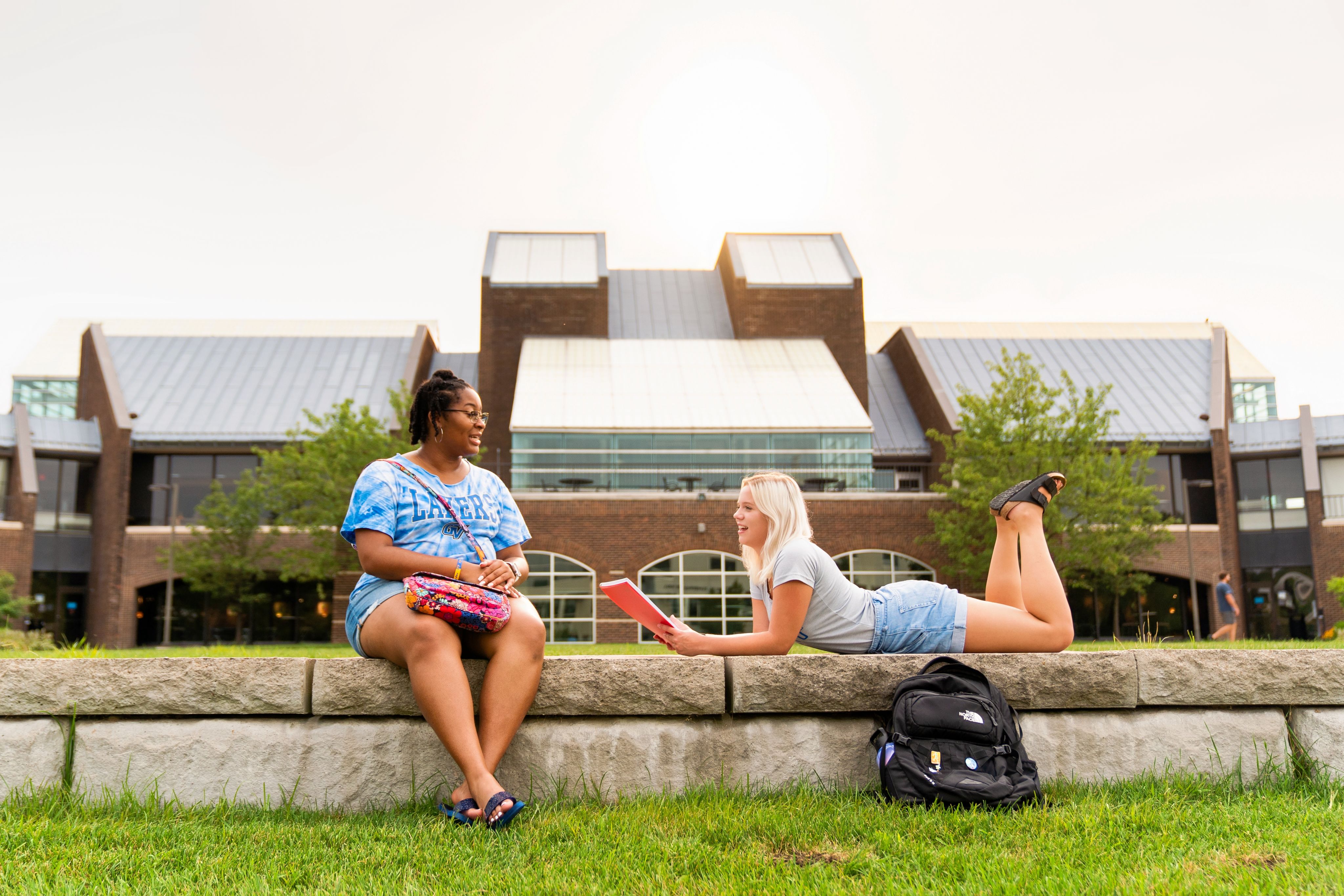 Two students sitting outside of Kirkhof talking