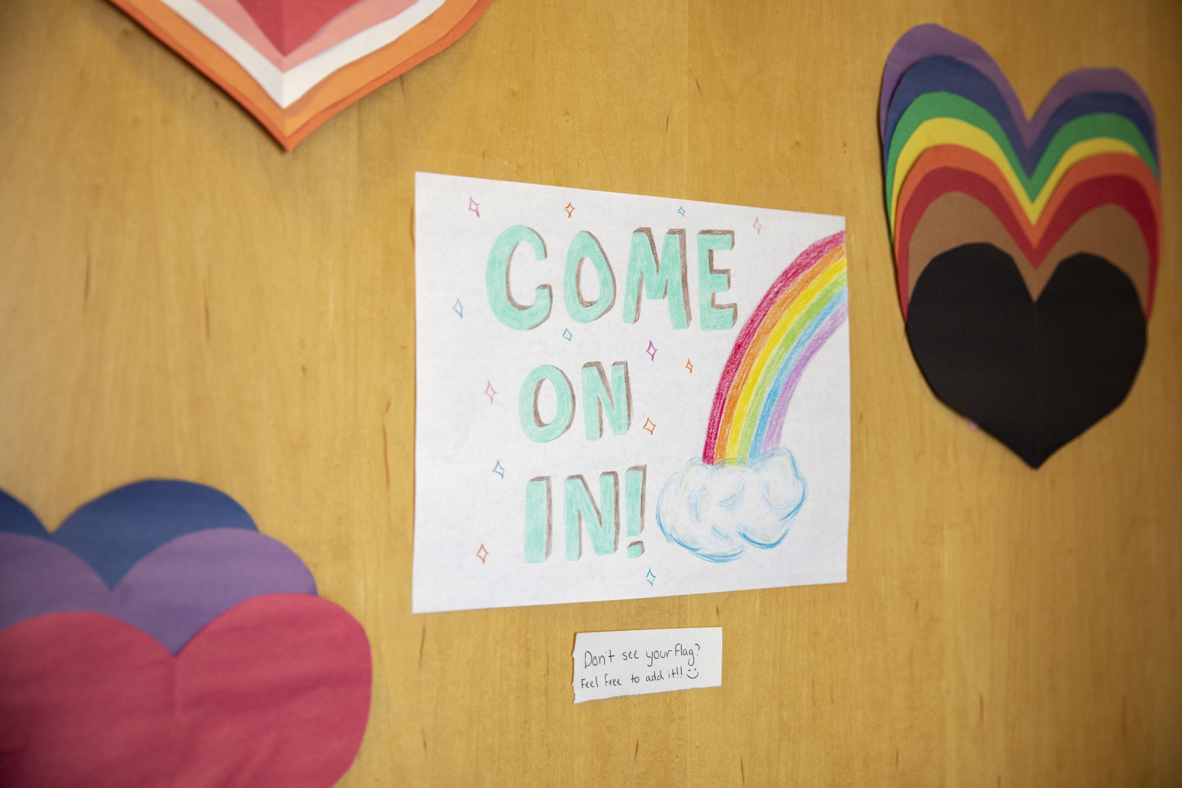 GVSU LGBT Resource Center door with a Come on In sign with a rainbow and paper hearts displayed on the door